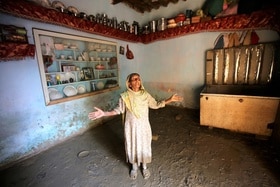 una donna in Pakistan allarga le braccia e guarda verso l alto all interno della sua abitazione