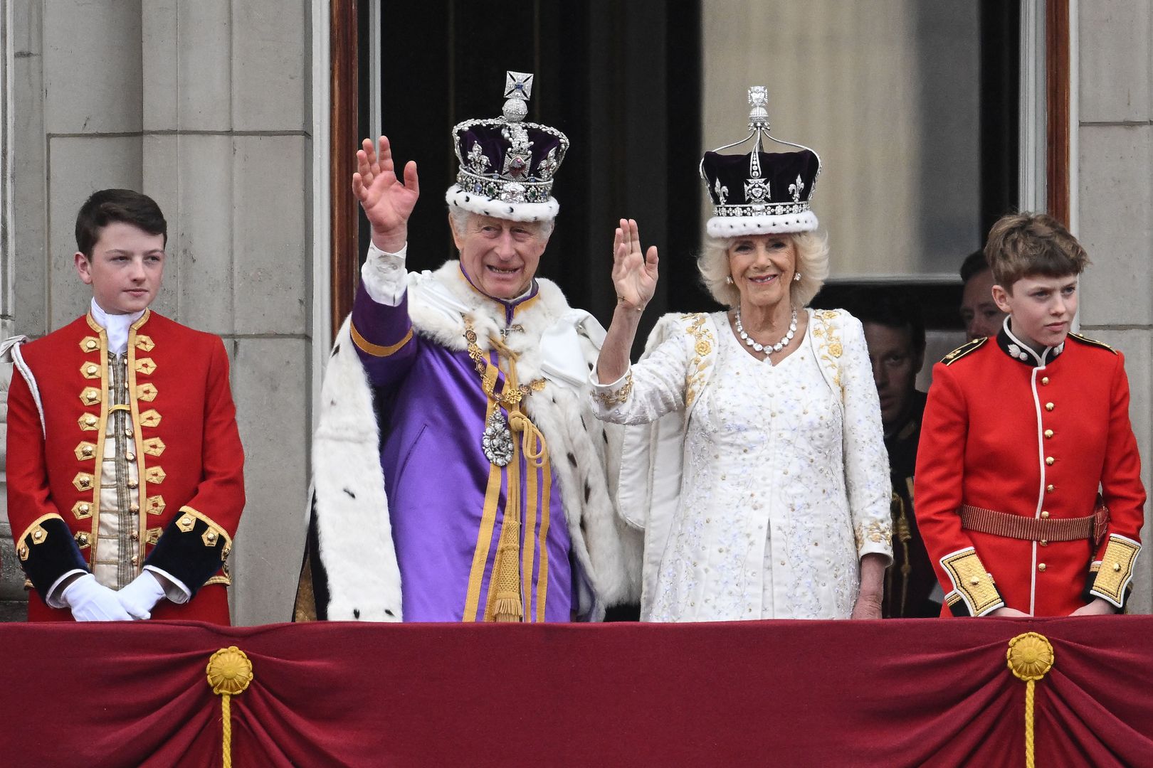 Britain's King Charles III wearing the Imperial state Crown, and Britain's Queen Camilla wearing a modified version of Queen Mary's Crown wave from the Buckingham Palace balcony after viewing the Royal Air Force fly-past in central London on May 6, 2023, after their coronations. - The set-piece coronation is the first in Britain in 70 years, and only the second in history to be televised. Charles will be the 40th reigning monarch to be crowned at the central London church since King William I in 1066. (Photo by Marco BERTORELLO / AFP)