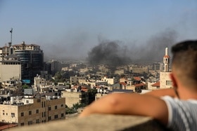 Enfant regardant un immeuble enfumé dans une ville palestinienne