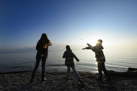 Trois enfants lançant des pierres dans le lac Léman