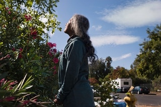 A person looking up to the sun, a trailer can be seen in the background.