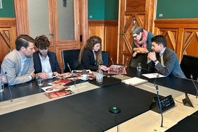 Cinq personnes assises à une table au Palais fédéral