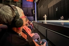 Femme portant un casque audio, assise au premier rang d une salle de théâtre