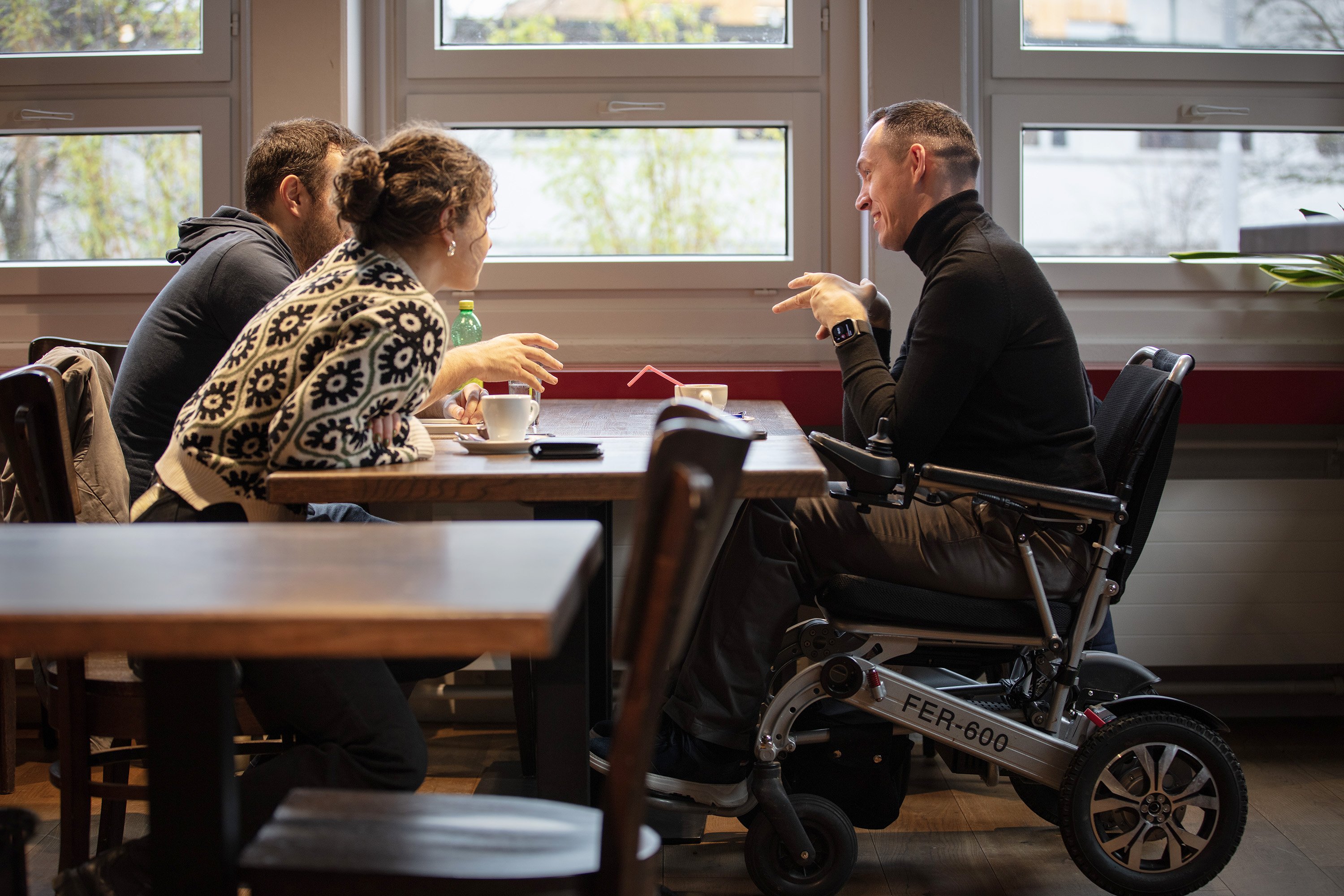 Trois personnes autour d'une table, dont une en fauteuil roulant