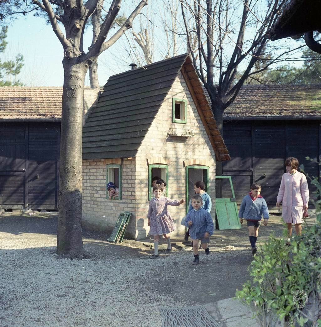 Instructrice et quatre enfants dans une cour d école primaire en Italie autrefois