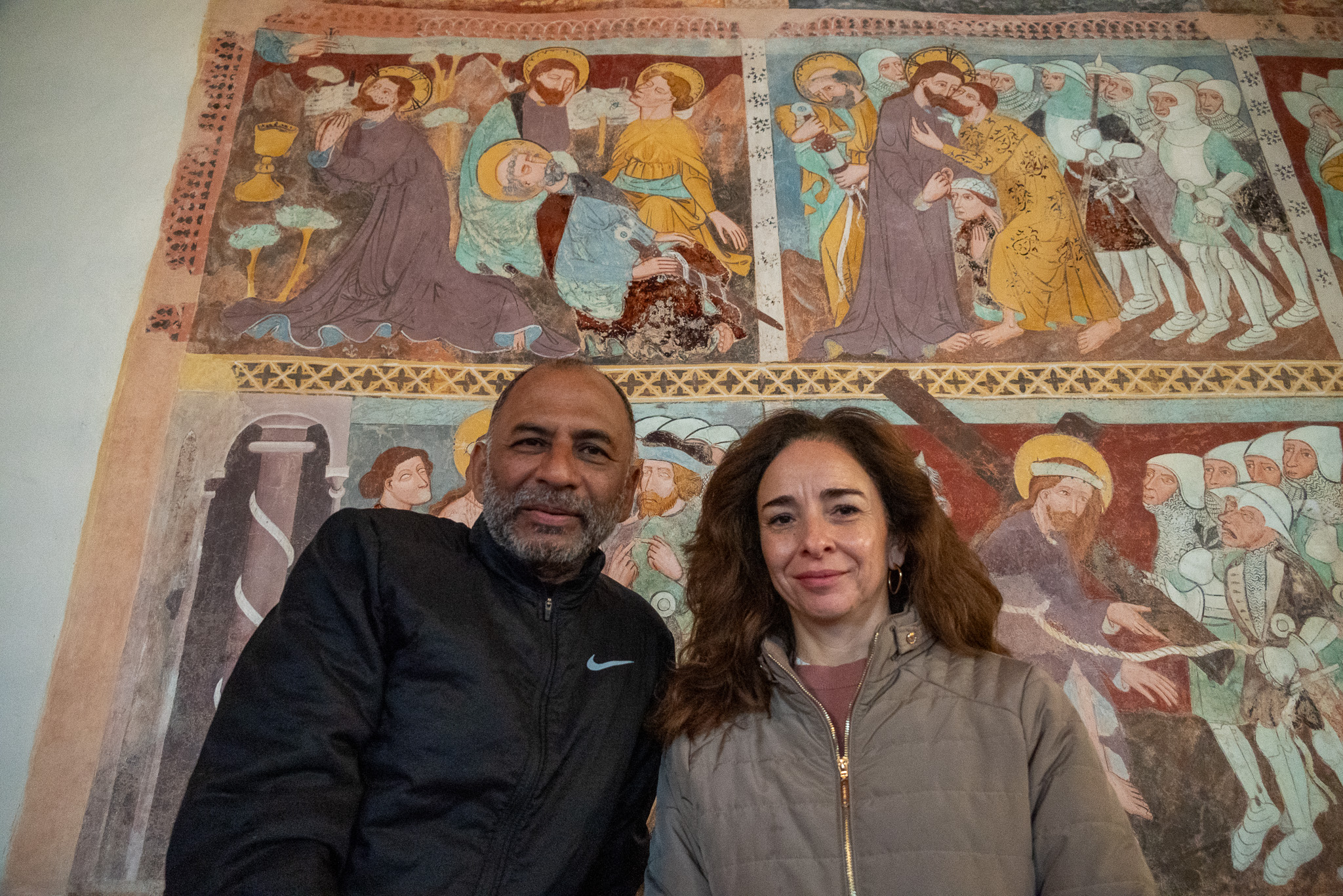 Un homme et une femme devant la fresque d'une église.