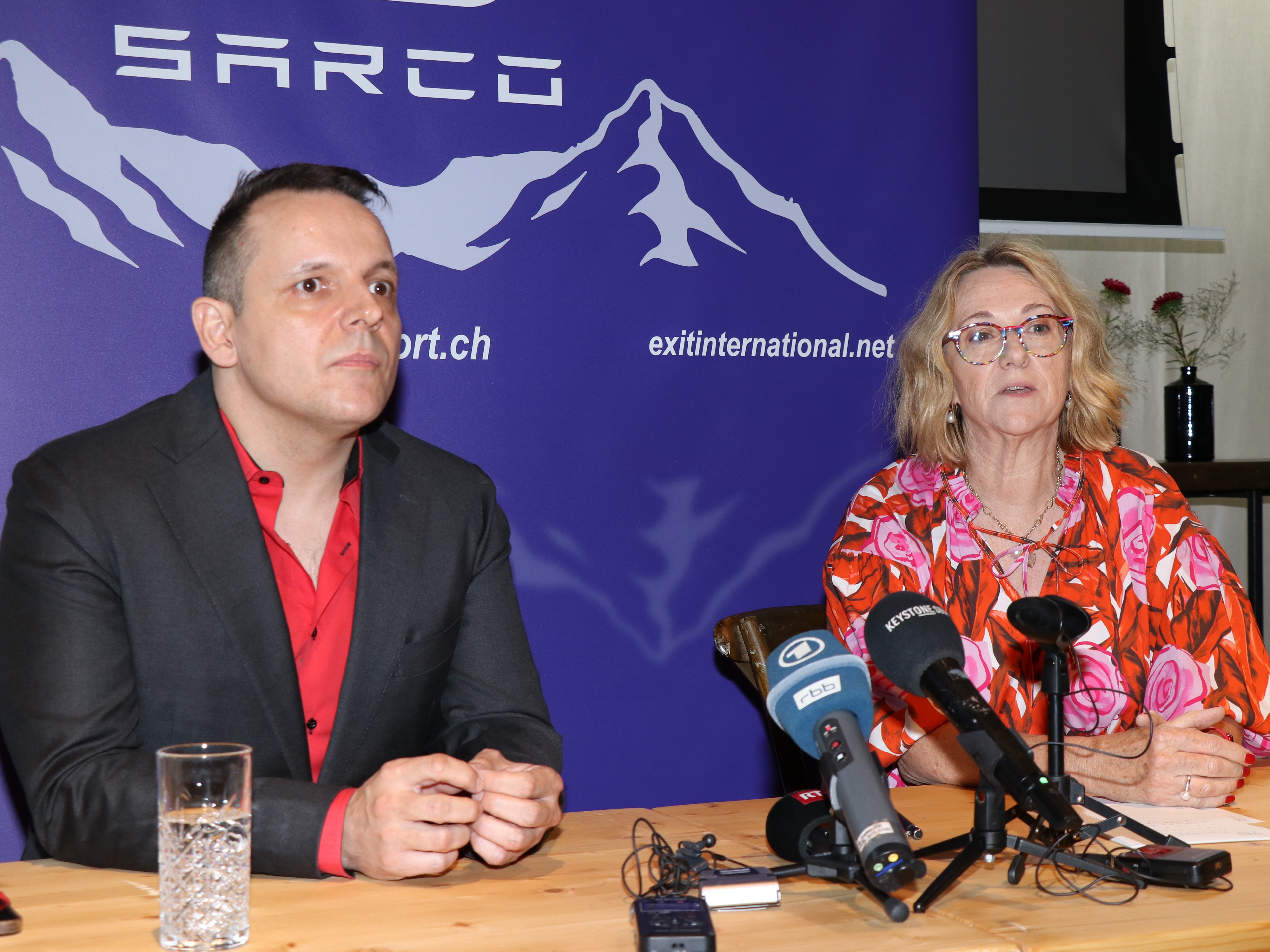 Un homme et une femme assis à une table lors d'une conférence de presse