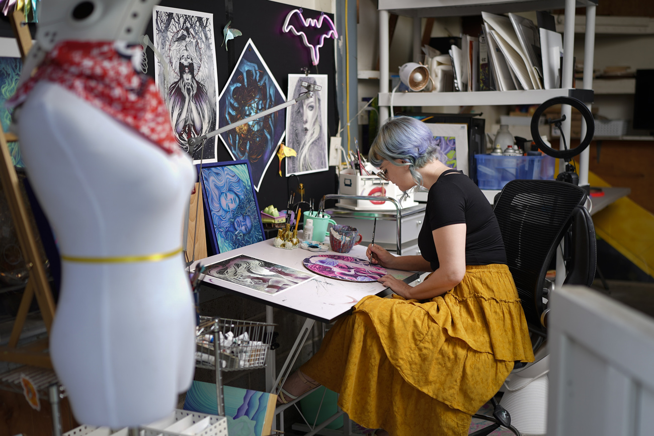 Femme assise devant une table à dessin en train de faire un travail créatif.