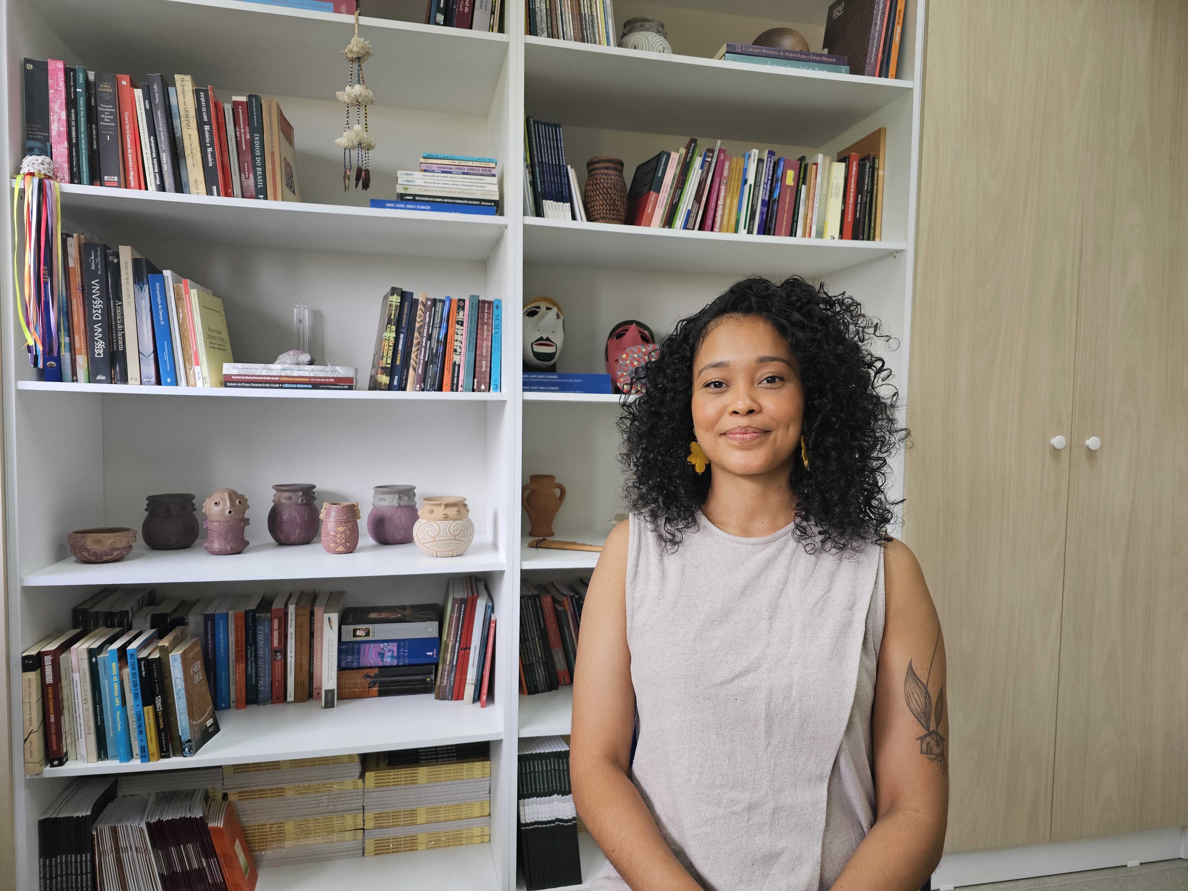 Jeune femme posant debout devant des livres.