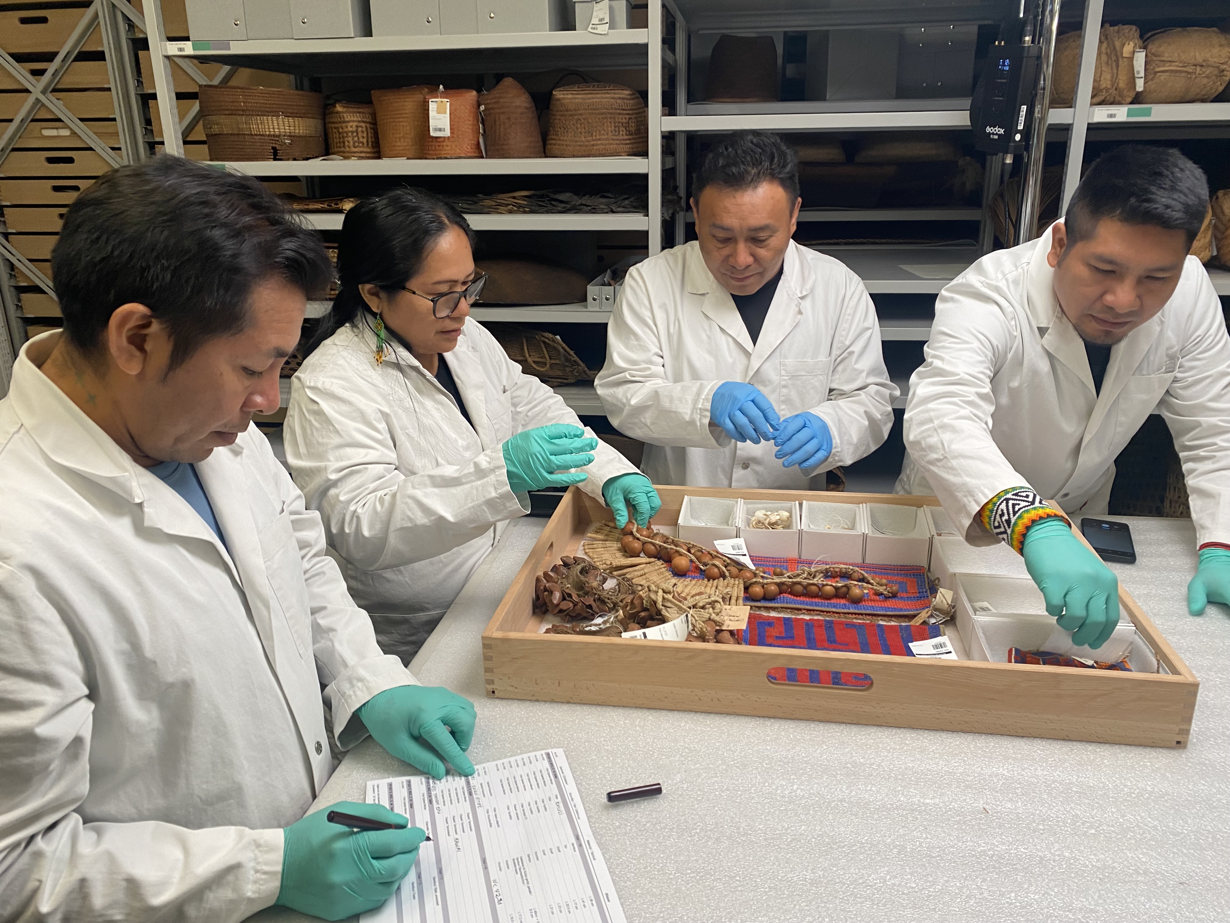 Groupe de personnes en blouse blanche travaillant sur des objets indigènes.