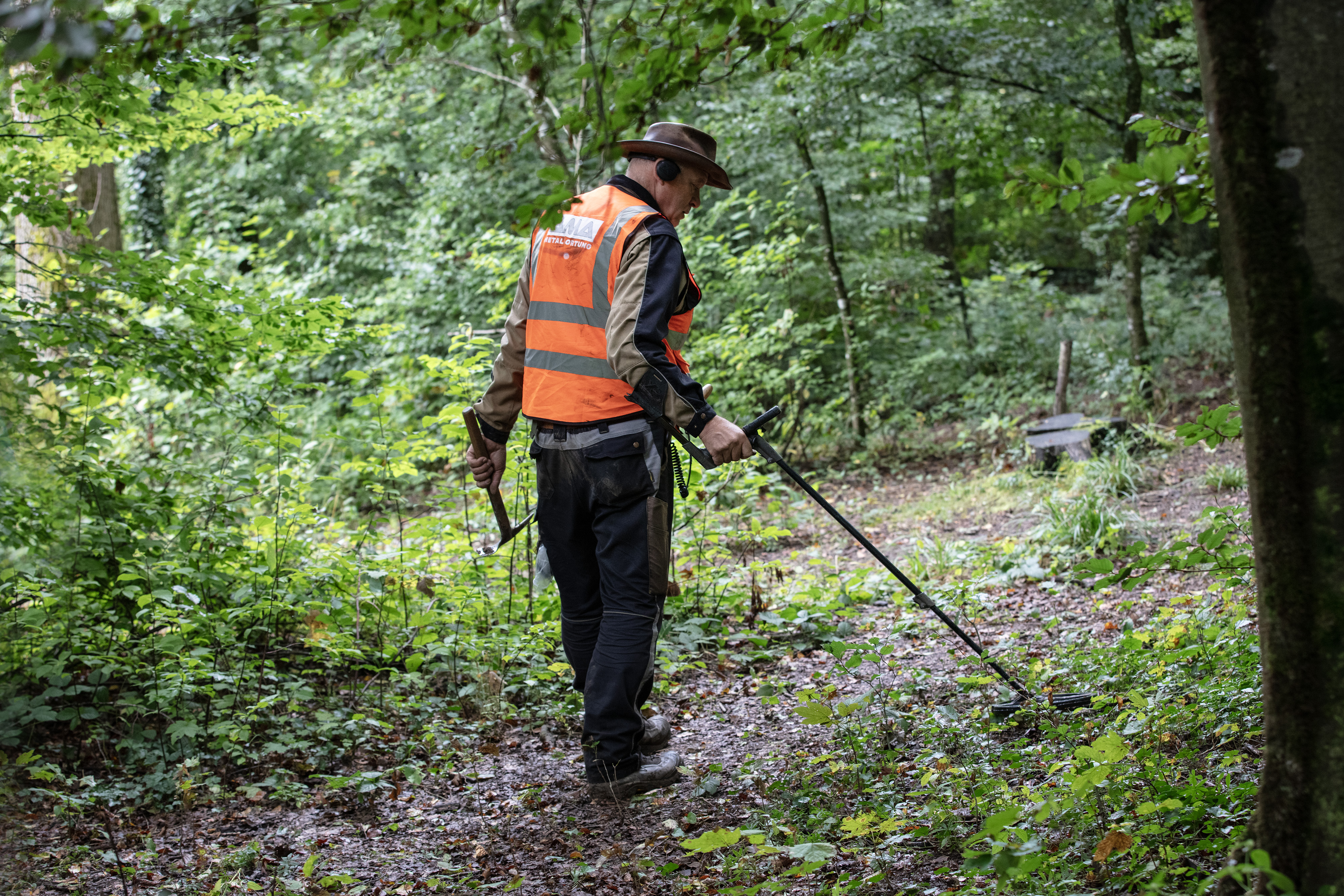 Homme faisant des recherches avec un détecteur de métaux dans une forêt.