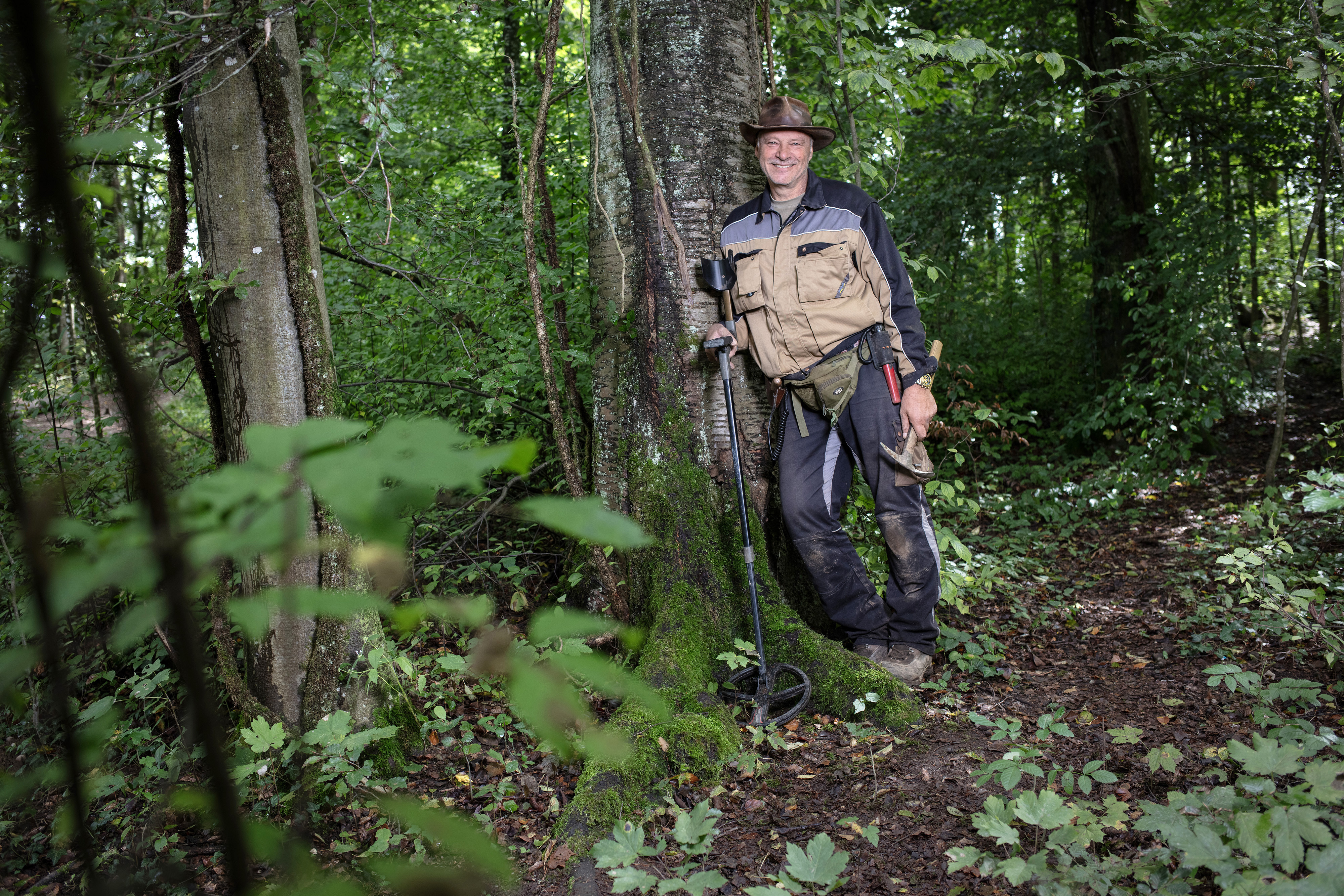 Homme appuyé contre un arbre dans une forêt