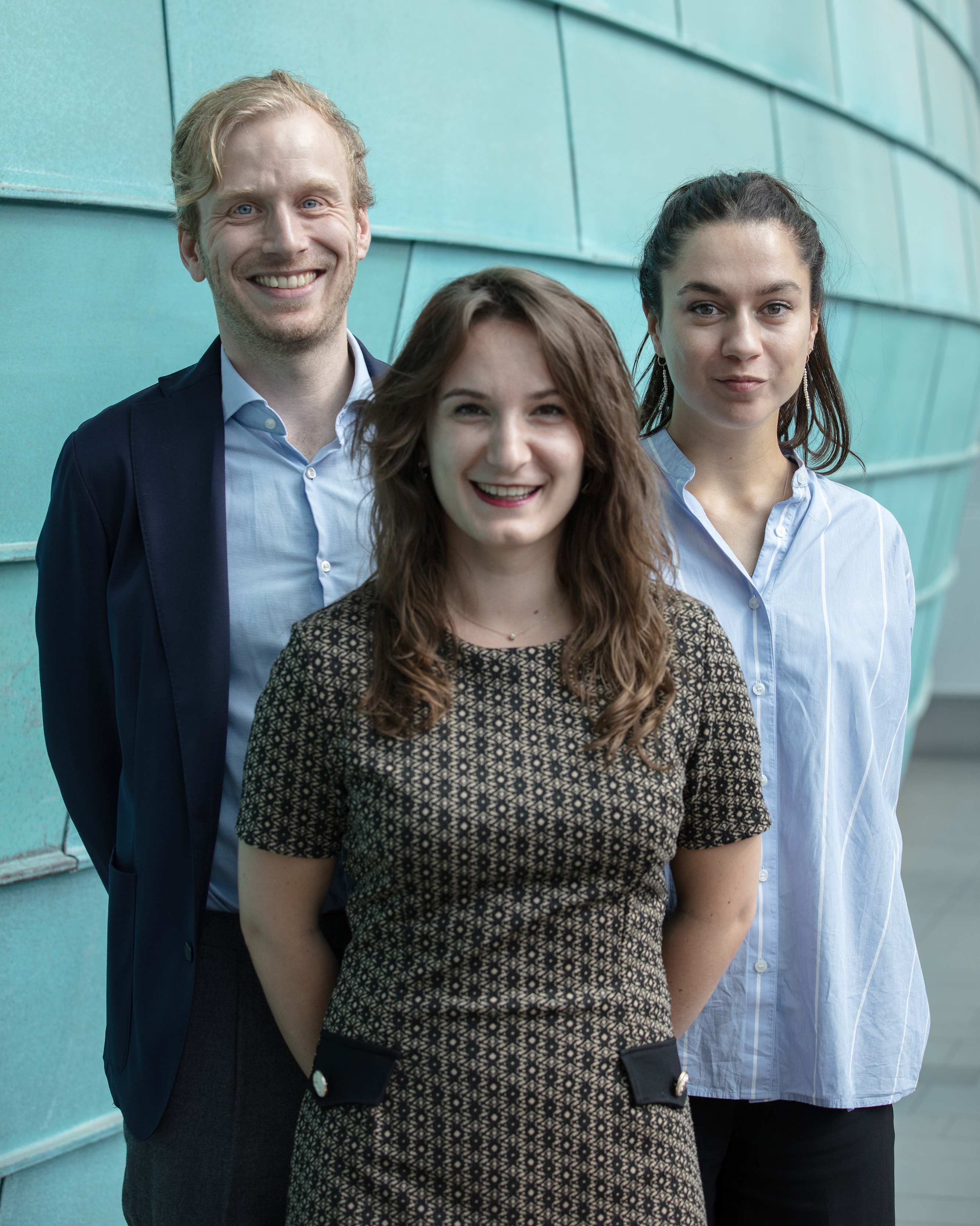 Deux femmes et un homme posant devant un mur.