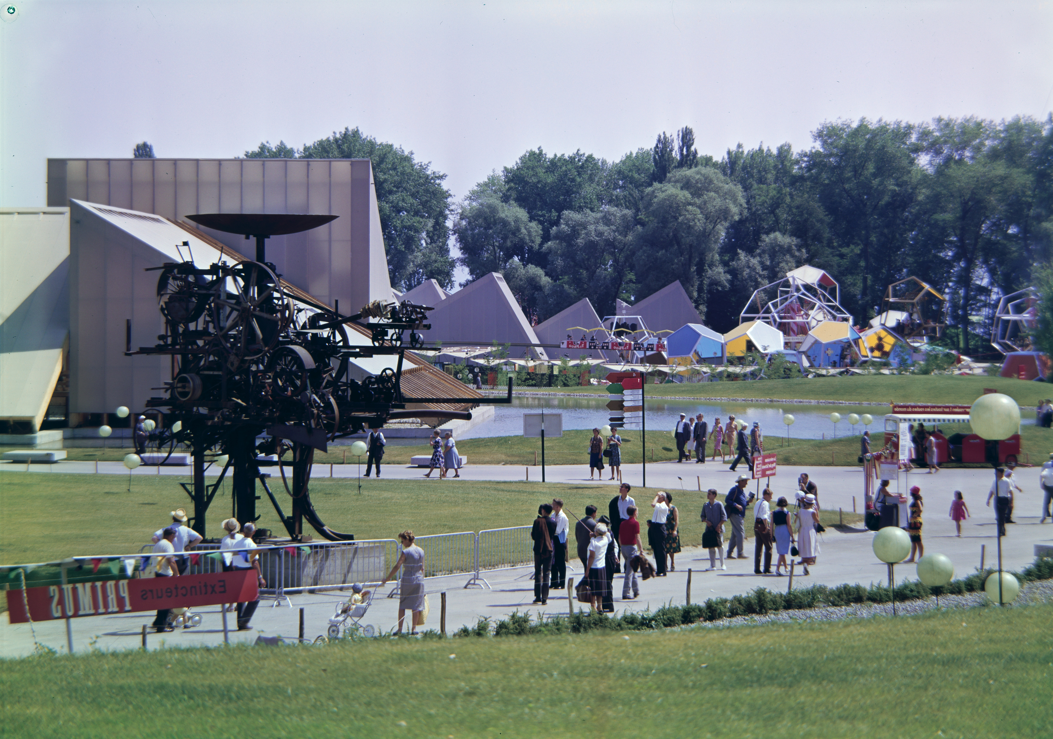 Site de l'exposition nationale suisse de 1964 avec du public et une sculpture.