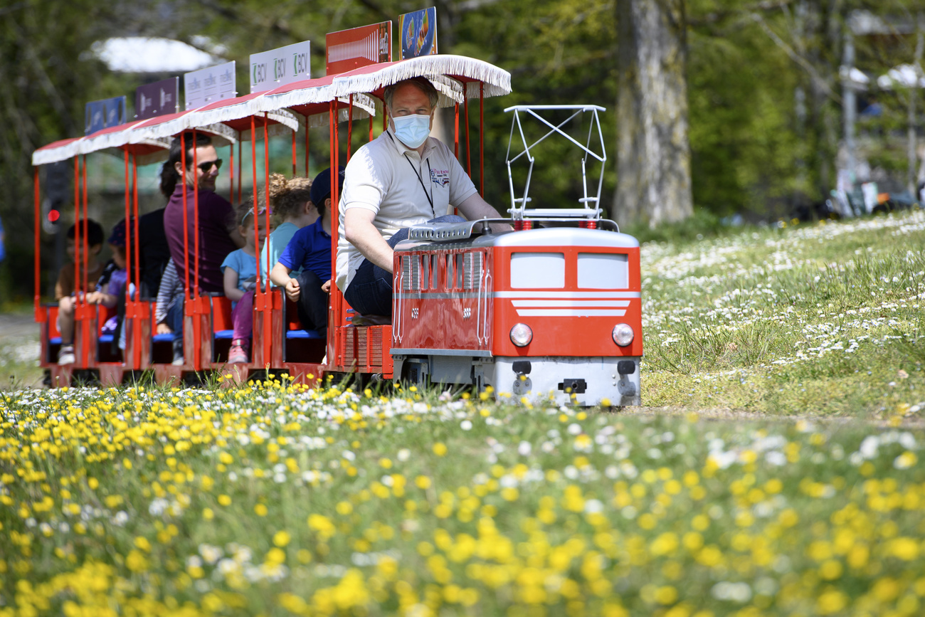 Mini train dans un parc avec son conducteur et des passagers.