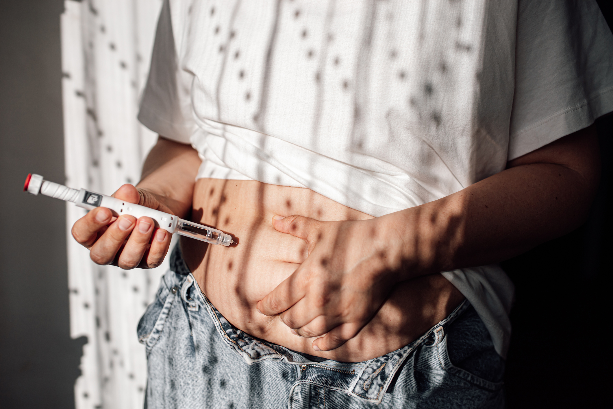 Une femme en train de se faire une injection dans le ventre.