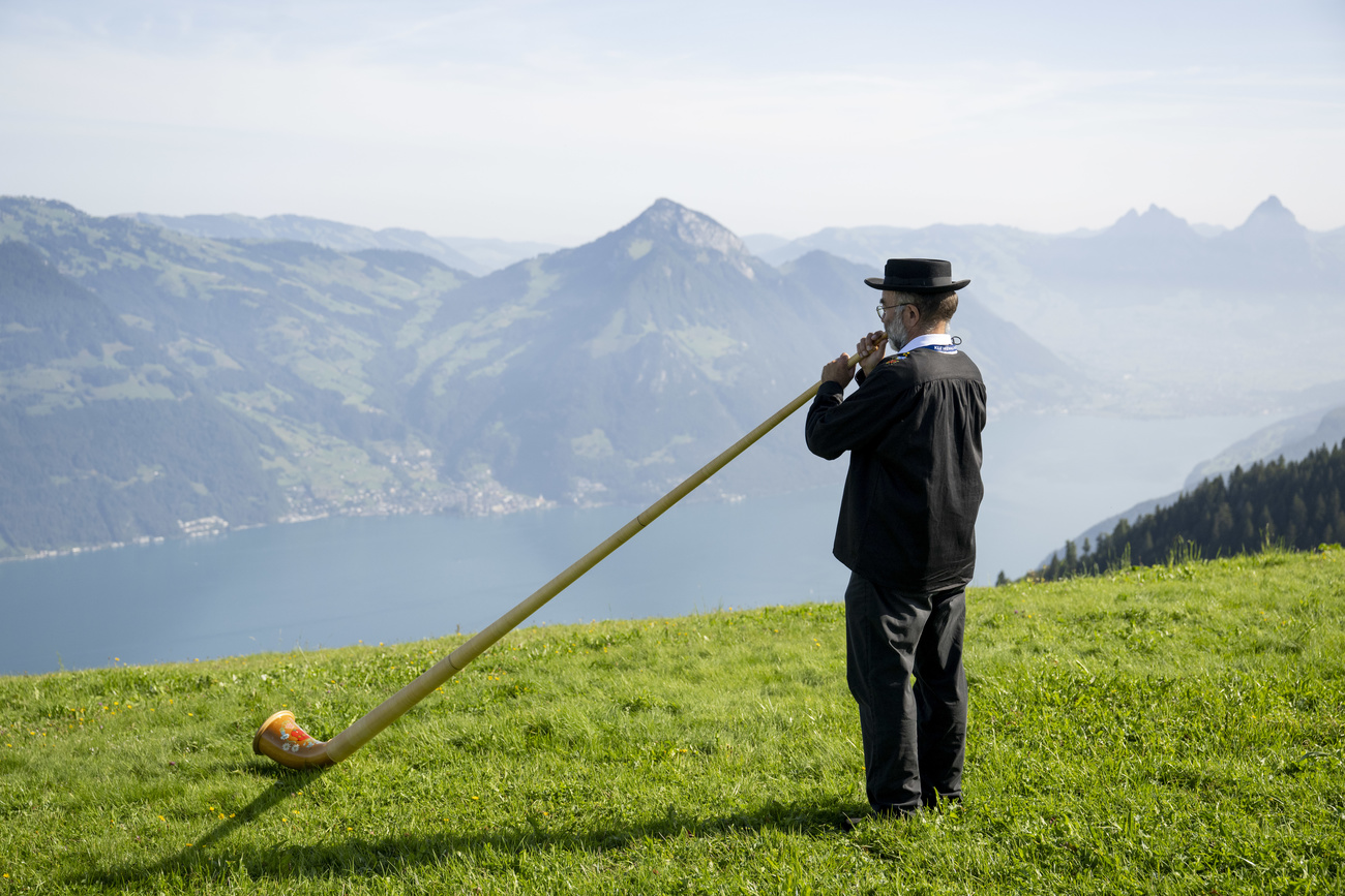 Homme jouant du cor des Alpes en montagne.