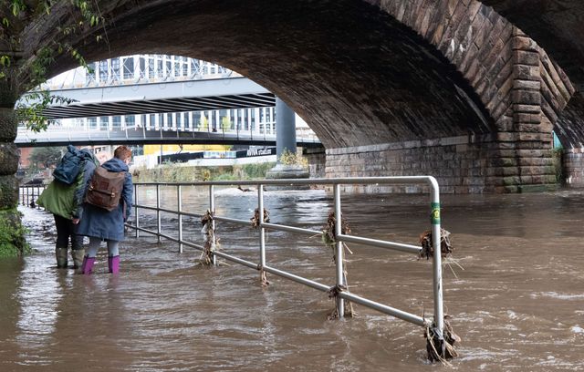 Un couple tente de poursuivre son chemin alors que la rivière Irwell, dans le centre de Manchester, est en crue.