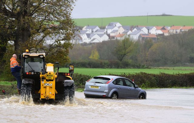 Des agriculteurs tentent d’aider un automobiliste dont la voiture a été coincée sur une route inondée, à Devon, en Angleterre, le 24 novembre 2024.