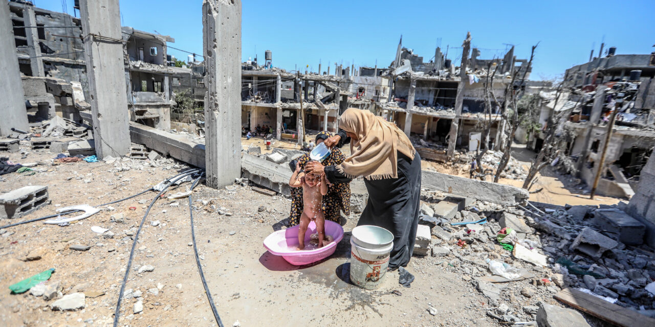 une mère nettoie son enfant dans les ruines