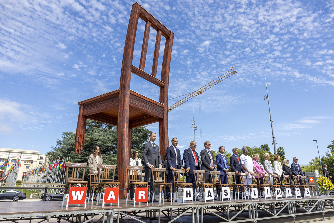 Le ministre suisse des affaires étrangères Ignazio Cassis, à droite, et des invités posent derrière des chaises pour marquer le 75e anniversaire des Conventions de Genève sur la Place des Nations, devant le siège européen des Nations Unies à Genève, en août.