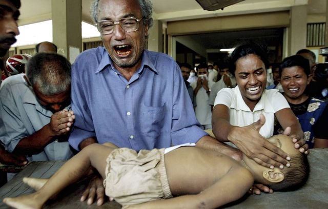 Le père d’une jeune victime du tsunami pleure avec d’autres membres de la famille alors qu’il tient le corps de son fils à l’hôpital de Galle, Sri Lanka, le 27 décembre 2004. Au total, le tsunami a fait 226.408 morts selon EM-DAT, une base de données mondiale reconnue sur les catastrophes, dont 35.000 personnes au Sri Lanka.