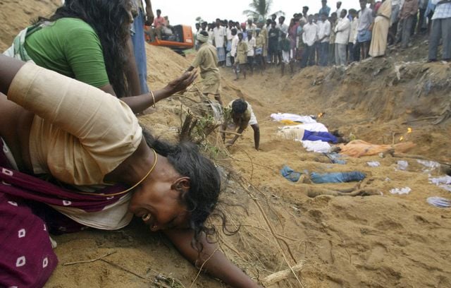 Les proches des victimes tuées par les vagues du tsunami pleurent sur le site d’un enterrement collectif à Cuddalore, en Inde, le lundi 27 décembre 2004.