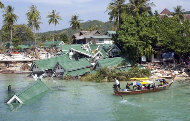 Un bateau passe devant un hôtel endommagé, dans la baie de Ton Sai, sur l’île de Phi Phi, en Thaïlande, le 28 décembre 2004. Dans le pays, plus de 5.000 personnes sont décédées dont la moitié étaient des touristes étrangers, et 3.000 autres ont été portées disparues.