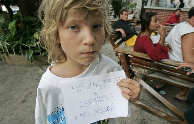 Karl Nilsson de Lulo, en Suède, pose avec une pancarte indiquant que ses parents et ses frères ont disparu, le 28 décembre 2004, à Phuket, en Thaïlande. Les parents des jeunes garçons ont été emportés en mer deux jours avant, lorsque le tsunami a frappé leur hôtel de plage juste au nord de Phuket, en Thaïlande.