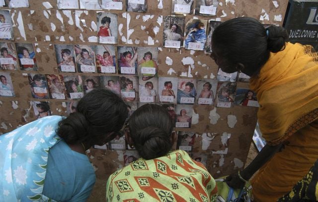 Les personnes qui ont perdu des membres de leur famille à cause du tsunami meurtrier tentent de les identifier à partir de photos prises avant leur enterrement collectif et publiées plus tard sur des panneaux pour aider les familles à identifier leurs morts, à Vailankanni, près de Nagapattinam, en Inde, le samedi 8 janvier 2005.