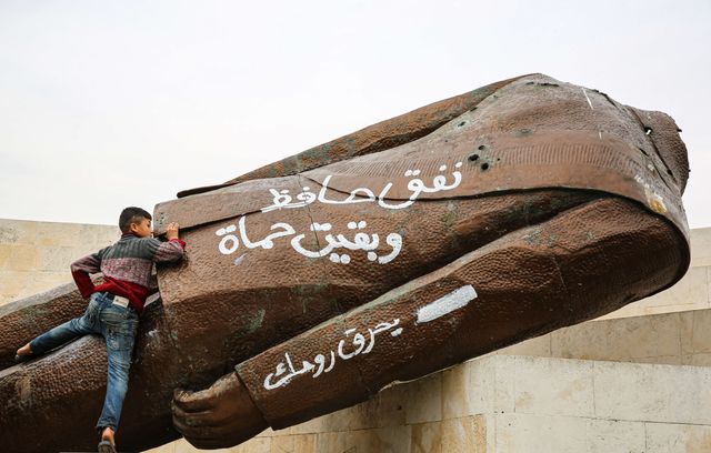 Un enfant escalade la statue déboulonnée de l’ancien président syrien Hafez el-Assad, père de Bachar el-Assad, démolie dans la ville syrienne de Hama, suite à l’avancée des groupes rebelles syriens dirigés par Hayat Tahrir al-Sham. De nombreux enfants ont posé près de cette statue. A travers le pays, d’autres manifestants ont déboulonné les statues d’Assad père et fils, comme à Alep, dans le Nord, ou à Deraa, dans le Sud.