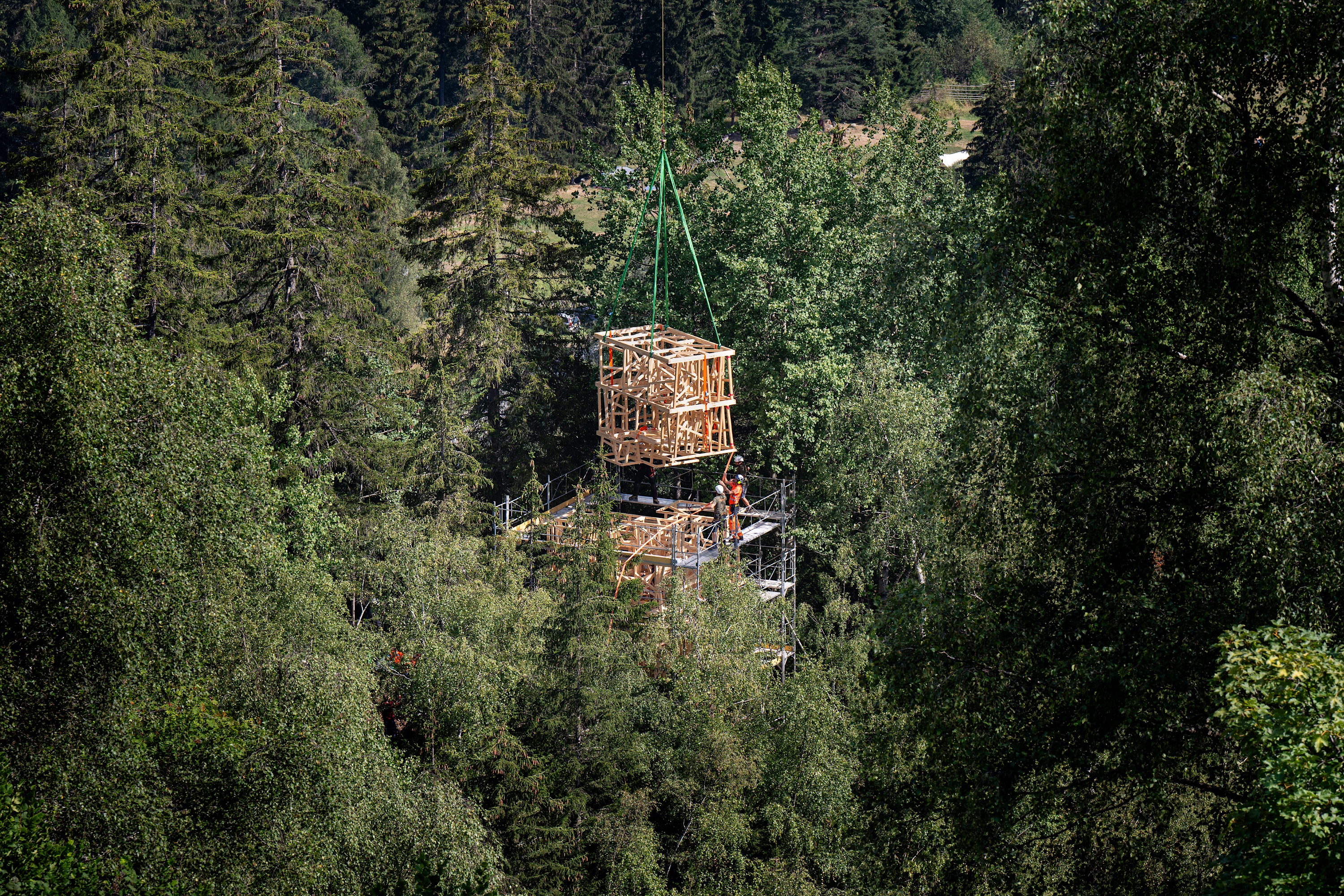 Hélicoptère déposant de modules de construction en bois dans une forêt.