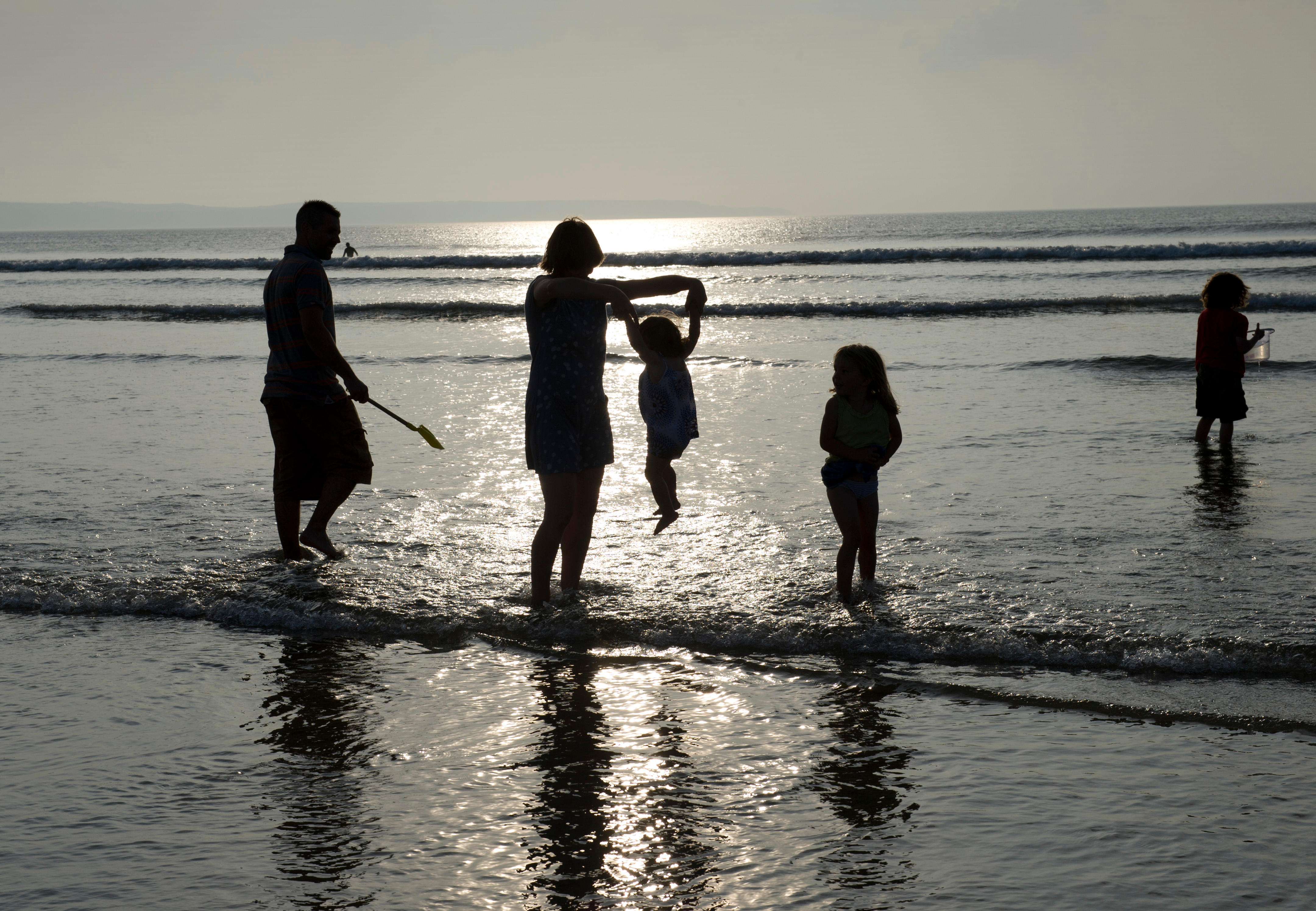 Une famille de cinq personnes pagayant dans la mer au coucher du soleil