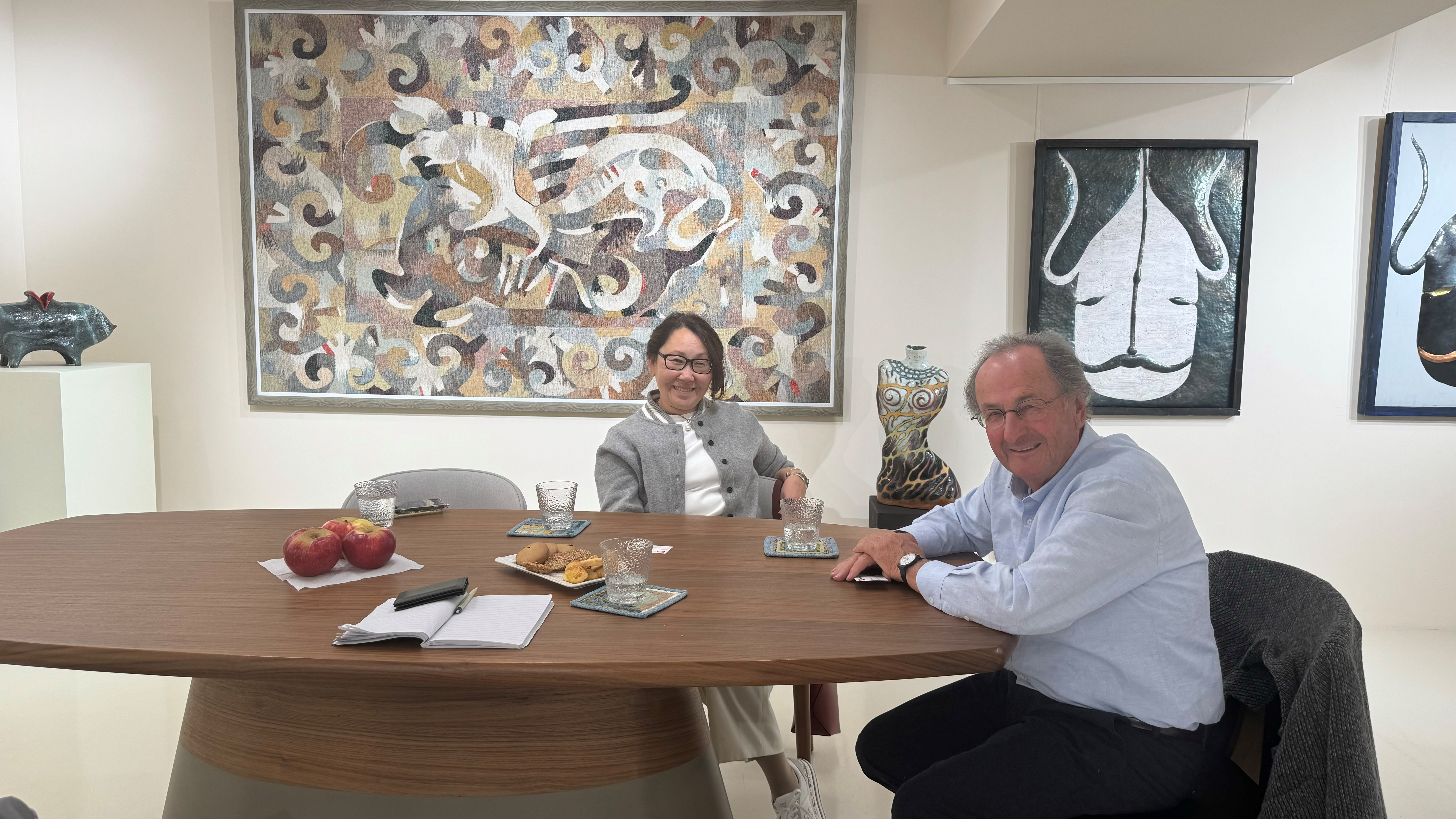 Un homme et une femme assis à une table avec des tableaux en arrière-fond