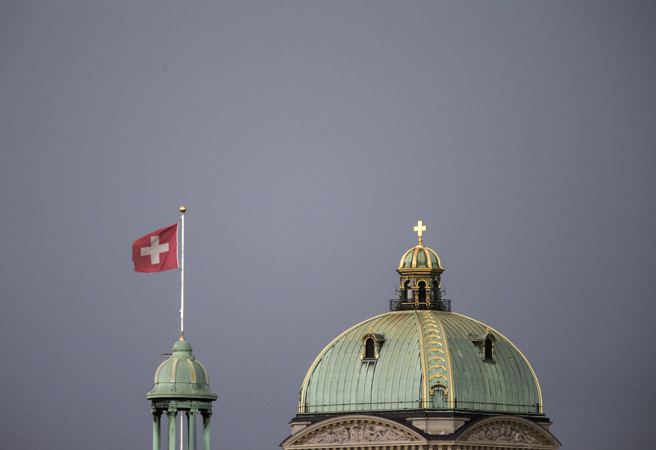 Drapeau suisse flottant à côté de la coupole du Palais fédéral de Berne.