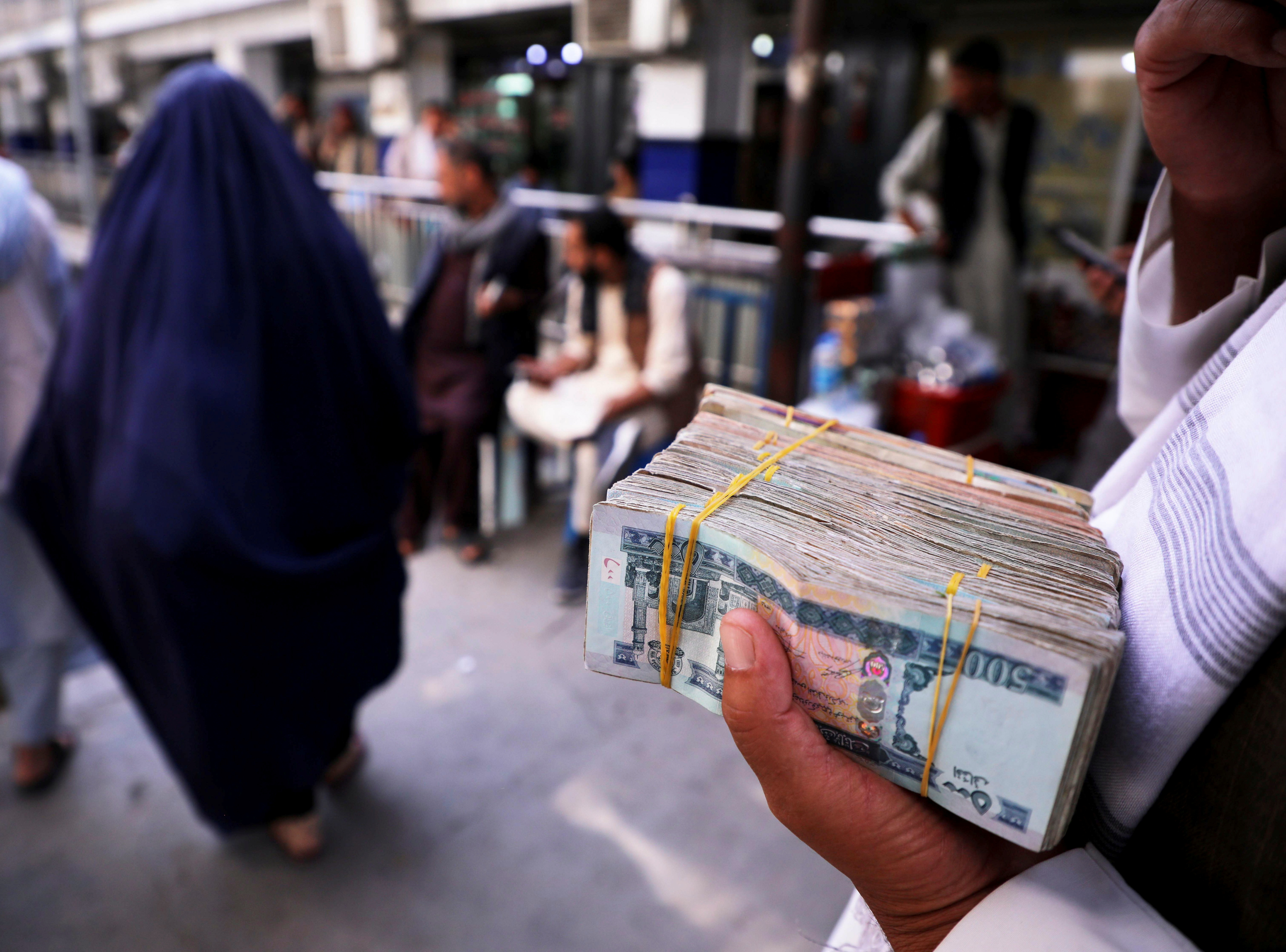 Une personne tient une liasse de billets de banque afghans dans un marché de change, à la suite de la réouverture des banques et des marchés après la prise de pouvoir des talibans à Kaboul, le 4 septembre 2021.