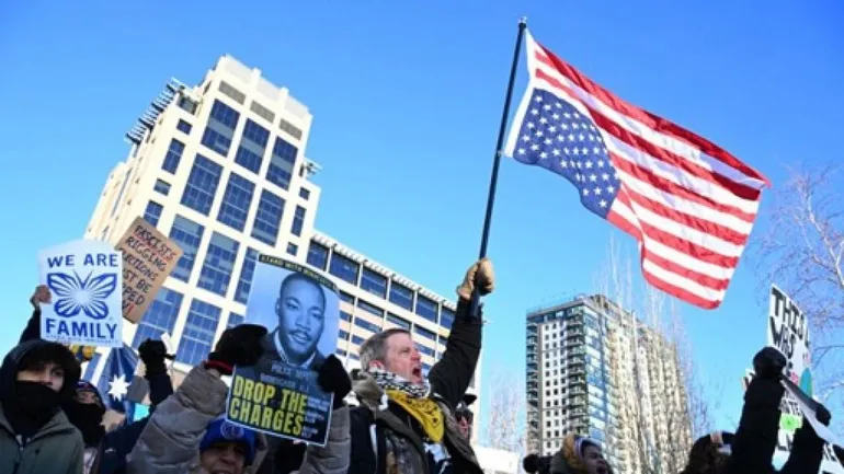 Un homme brandit un drapeau américain à l’envers lors d’une manifestation contre l’agence américaine de contrôle de l’immigration et des douanes (ICE) à Minneapolis, dans le Minnesota, le 30 janvier 2026.