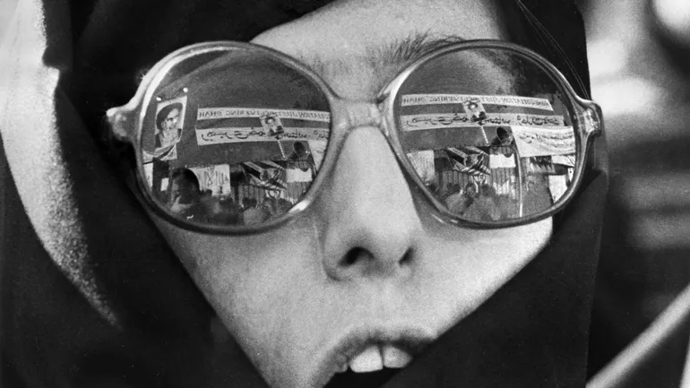 Le reflet des slogans de l’ayatollah Khomeini dans les lunettes d’une femme iranienne.