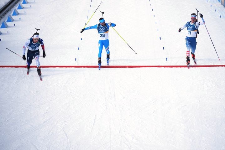 Fabien Claude, de France, de gauche à droite, Nicola Romanin, d'Italie, et Campbell Wright, des États-Unis, franchissent la ligne d'arrivée de la course masculine de biathlon de 15 kilomètres avec départ groupé aux Jeux olympiques d'hiver de 2026 à Anterselva, en Italie, le vendredi 20 février 2026. (AP Photo/Andrew Medichini) /OLYAG178/26051542380213/2602201607