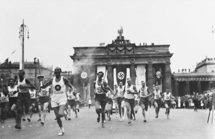 Un porteur de la flamme olympique passe la porte de Brandebourg à Berlin pour se rendre à la cérémonie d'ouverture des Jeux olympiques de Berlin le 1er août 1936.