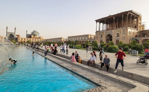 Des gens s'asseyent près de la fontaine sur la place historique Naqsh-e Jahan, près du palais Ali Qapu (Grande Porte), qui servait autrefois de résidence officielle aux empereurs perses de la dynastie safavide (1501-1736), dans la ville centrale d'Ispahan, en Iran, le 17 mai 2022.