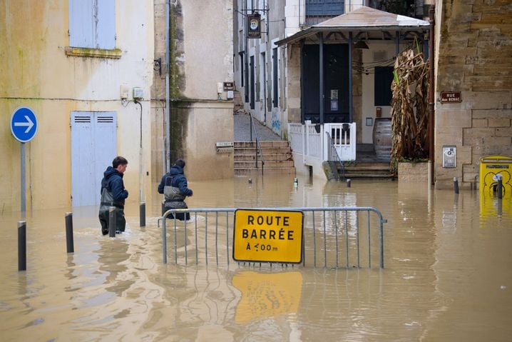 Des employés municipaux marchent dans une rue inondée de La Reolle, dans l'ouest de la France, au milieu de la tempête Nils, en février.