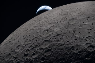 art002e009289 (6 avril 2026) – La surface lunaire remplit le cadre avec des détails nets, comme observé lors du survol lunaire d'Artemis II, tandis qu'une Terre lointaine se couche en arrière-plan. Cette image a été capturée à 18h41 EDT, le 6 avril 2026, juste trois minutes avant que le vaisseau Orion et son équipage ne passent derrière la Lune et perdent le contact avec la Terre pendant 40 minutes avant d'émerger de l'autre côté. Dans cette image, la partie sombre de la Terre est en pleine nuit, tandis que sur son côté de jour, des nuages tourbillonnants sont visibles au-dessus de l'Australie et de la région Océanie. Au premier plan, le cratère Ohm montre des bords en terrasses et un sol relativement plat marqué par des sommets centraux – formés lorsque la surface s'est redressée à la suite de l'impact qui a créé le cratère.