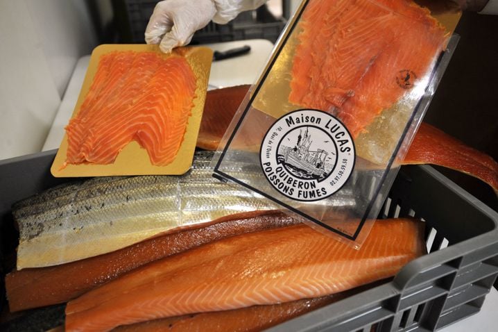 Le saumon fumé en tranches (ou la truite) est souvent présenté sur une plaque d'emballage alimentaire de couleur dorée, (Illustration)